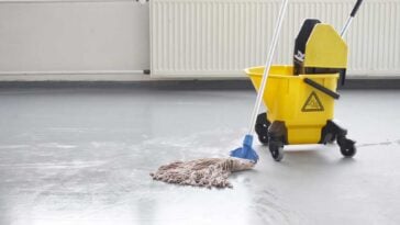 Mop and yellow bucket resting on grey concrete floors