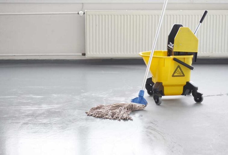 Mop and yellow bucket resting on grey concrete floors