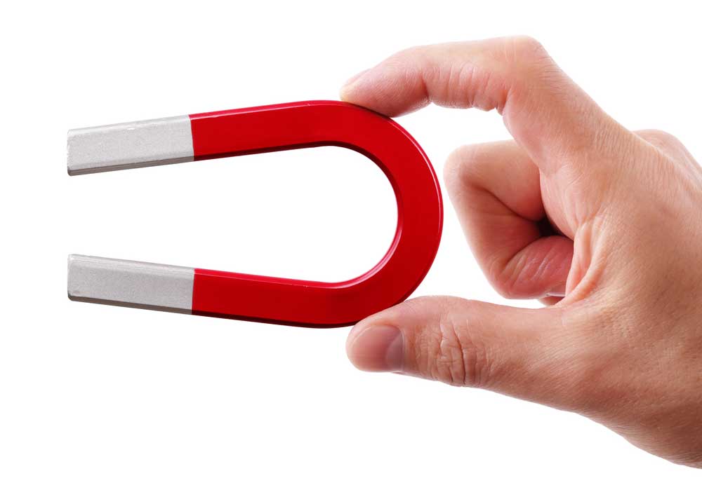 Two fingers holding a red and grey horseshoe style magnet on a white background