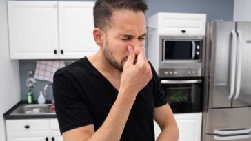 Man standing in the middle of his kitchen holding his nose