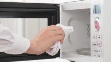 Hand holding white towel wiping out a microwave