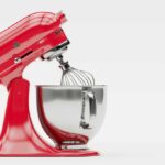 A red KitchenAid mixer with the head tilted back on a white background