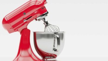 A red KitchenAid mixer with the head tilted back on a white background