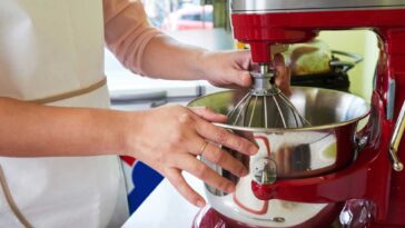 Person setting up whisk attachment on a red KitchenAid mixer