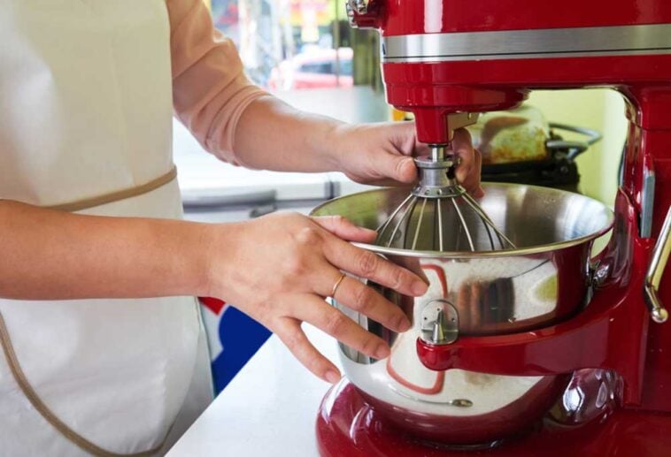 Person setting up whisk attachment on a red KitchenAid mixer