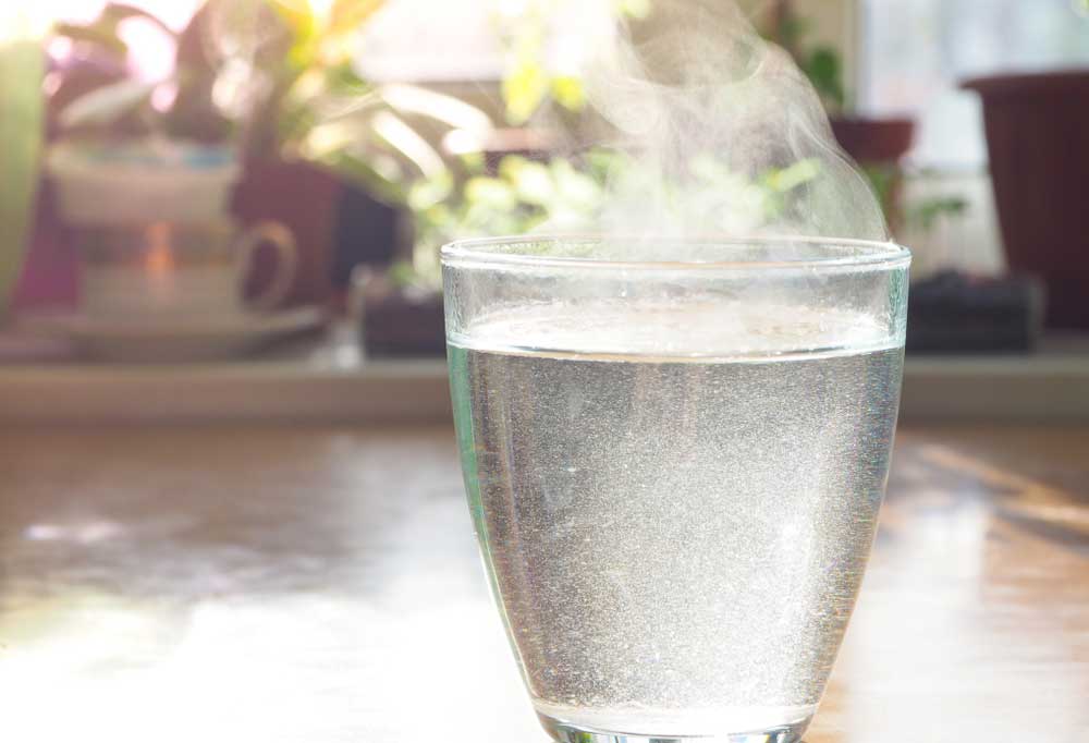 Clear tea cup of hot water on a kitchen counter
