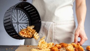 Chef pouring French fries from an air fryer basket onto a counter
