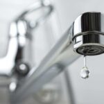 Close up of a dripping, chrome, kitchen faucet
