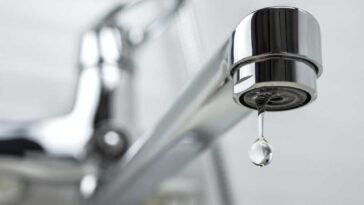 Close up of a dripping, chrome, kitchen faucet