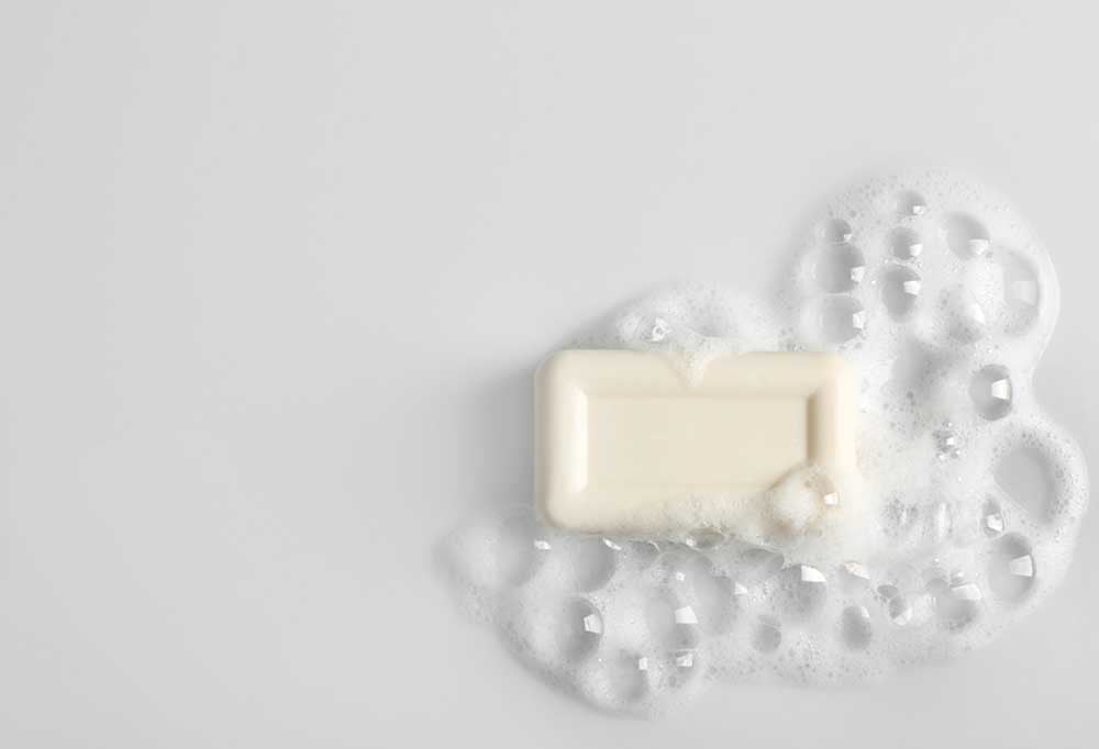 White bar of soap with suds on a white background.