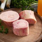 Raw beef bones cut into rounds and sitting on a cutting board