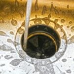 Water running down a sink drain with a garbage disposal installed