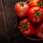 Bunch of tomatoes with stems in a bowl on a wooden table