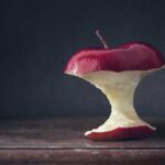 Apple core sitting on a wooden table with a dark background