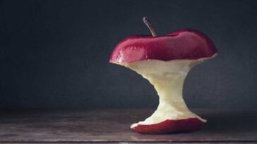 Apple core sitting on a wooden table with a dark background