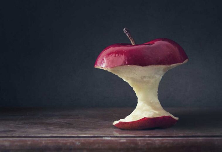 Apple core sitting on a wooden table with a dark background