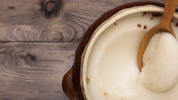 solid bacon grease in a stoneware pot with a wooden spoon in it