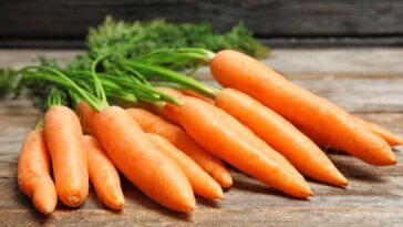 Carrots with stems laying on a wooden table
