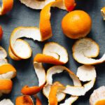 Oranges and orange peels on a slate background.