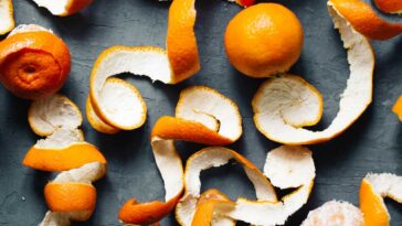 Oranges and orange peels on a slate background.