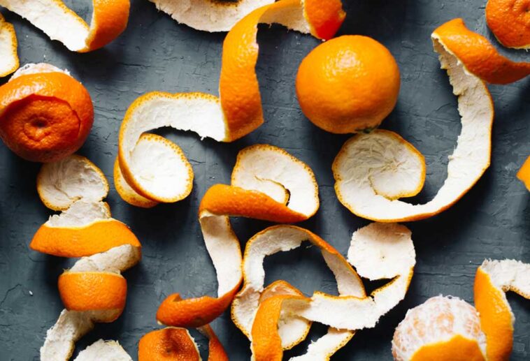 Oranges and orange peels on a slate background.