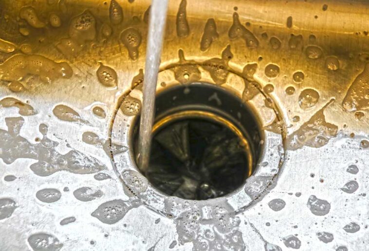 Water running down a sink drain with a garbage disposal installed