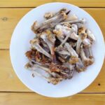 Fried chicken bones on a white dinner plate on a wooden table