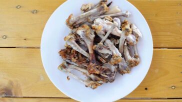 Fried chicken bones on a white dinner plate on a wooden table