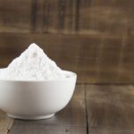 Baking soda in a white bowl on a wooden surface
