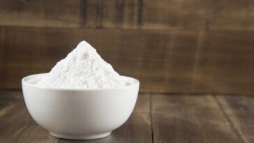 Baking soda in a white bowl on a wooden surface