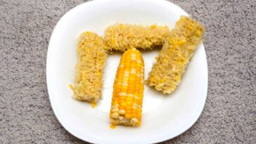 empty corn cobs with one whole ear of corn in the middle all on a white plate