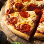 Close up of a pizza with a slice being removed