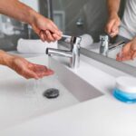 Person washing their hands at a countertop with sink- all in one-
