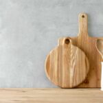 Wooden countertop with wooden cutting boards and cooking utensils leaning against the wall