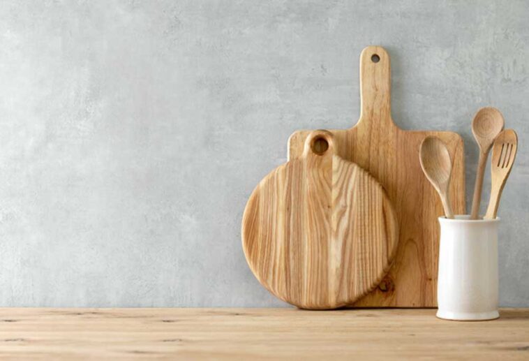 Wooden countertop with wooden cutting boards and cooking utensils leaning against the wall