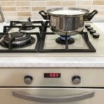 Gas kitchen range with a stainless steel pot on one burner