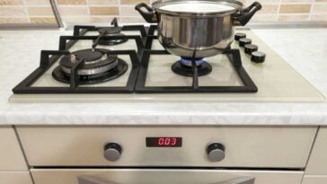 Gas kitchen range with a stainless steel pot on one burner