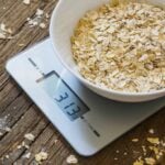 Digital kitchen scale with a bowl of oats in it being weighed
